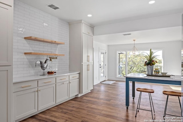 kitchen featuring decorative backsplash, light countertops, visible vents, and dark wood-type flooring