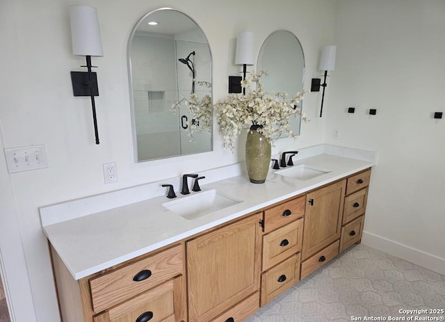 full bath featuring a shower stall, baseboards, a sink, and double vanity