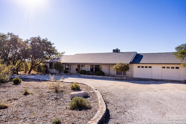 ranch-style house with an attached garage, a chimney, and driveway