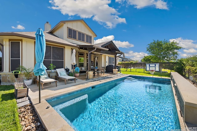 rear view of property with outdoor lounge area, a fenced in pool, a chimney, board and batten siding, and a patio