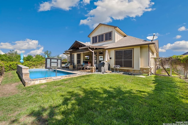 back of property featuring board and batten siding, an outdoor pool, and a yard