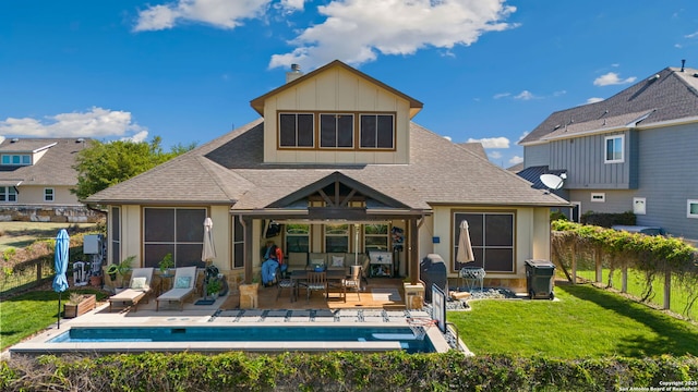 rear view of house with an outdoor pool, a shingled roof, a yard, board and batten siding, and a patio