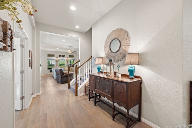 hall featuring stairs, wood finished floors, a textured wall, baseboards, and recessed lighting