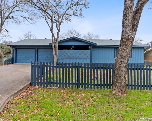 view of front of property featuring a garage, concrete driveway, and a fenced front yard