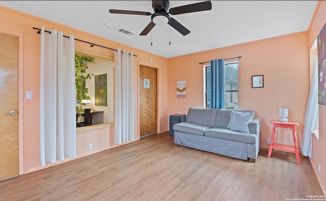 living room with light wood-style floors, visible vents, and ceiling fan