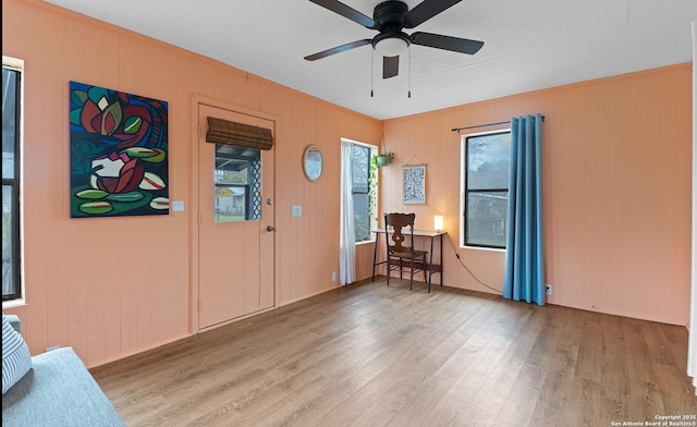 entrance foyer with a ceiling fan, wood finished floors, and wooden walls