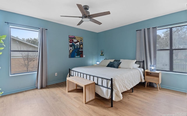 bedroom featuring baseboards, multiple windows, and wood finished floors