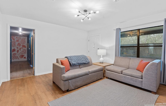 living room with baseboards, a chandelier, and light wood-type flooring