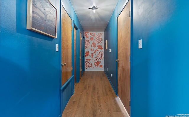 corridor featuring baseboards and wood finished floors
