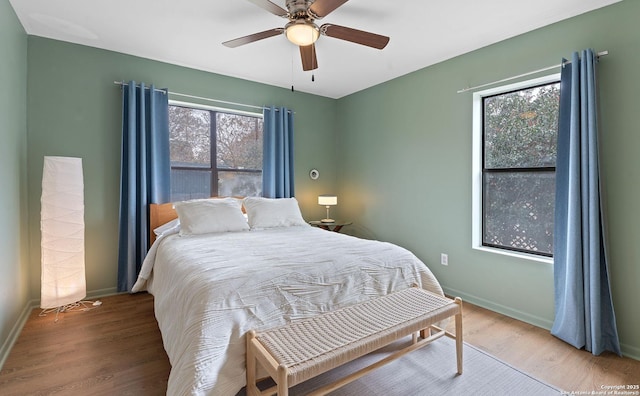 bedroom with wood finished floors, baseboards, and multiple windows