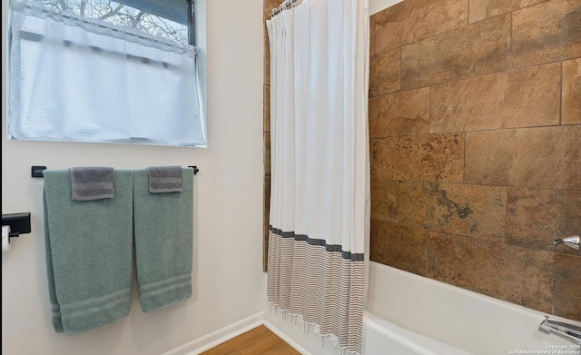 bathroom with baseboards and shower / bathtub combination with curtain