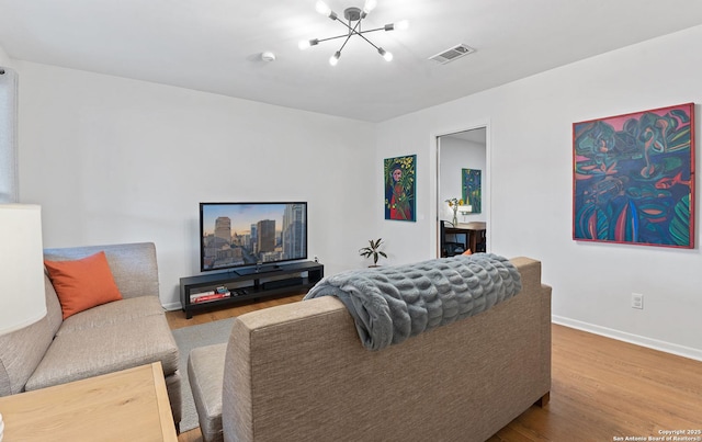 living area with a chandelier, wood finished floors, visible vents, and baseboards