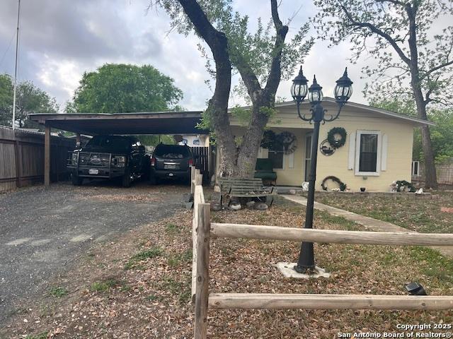 404 W Polk, Sabinal, TX 78881 - view of front facade with fence, a carport, and dirt driveway