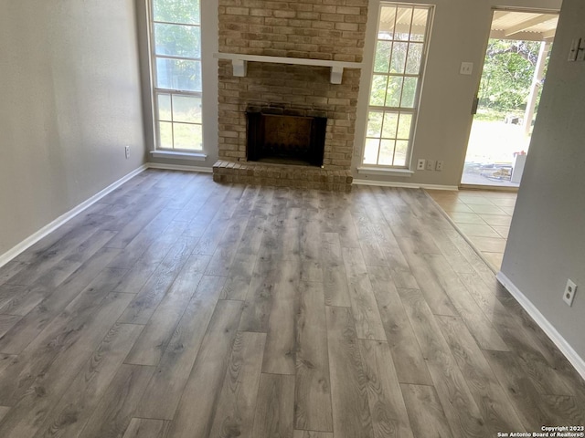 unfurnished living room featuring a fireplace, wood finished floors, and baseboards
