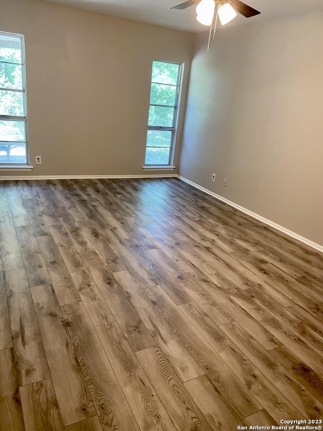unfurnished room featuring wood finished floors, a ceiling fan, and baseboards