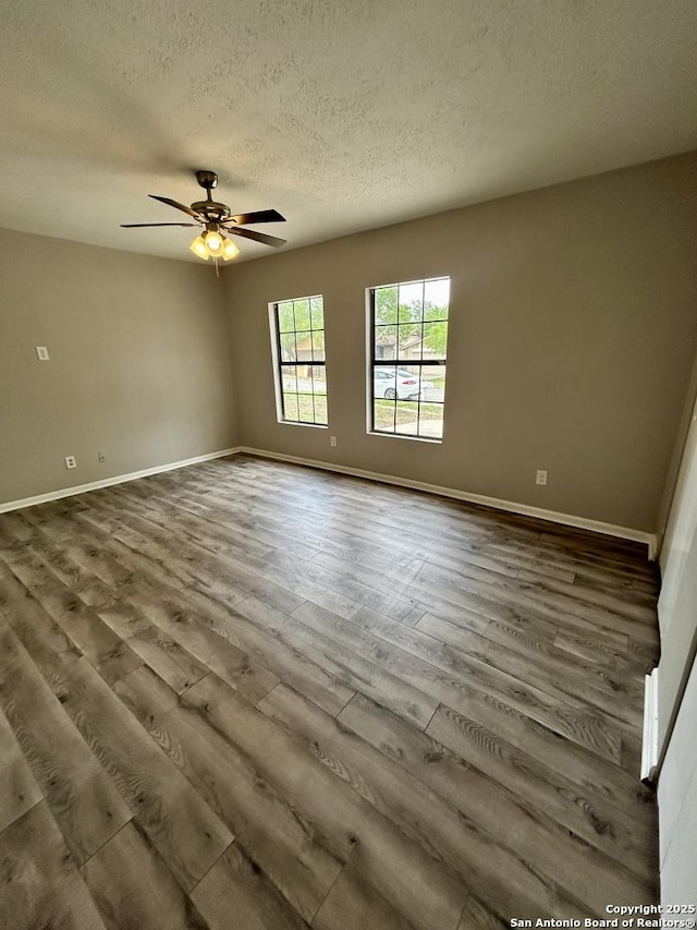 spare room featuring a textured ceiling, a ceiling fan, baseboards, and dark wood-style flooring