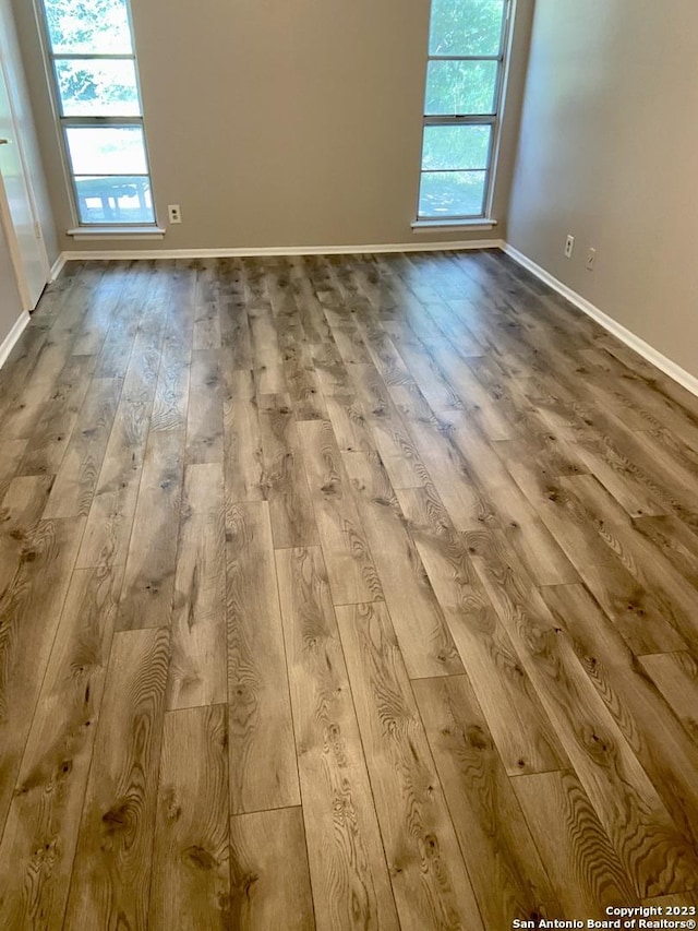 unfurnished room with hardwood / wood-style flooring, baseboards, and a healthy amount of sunlight