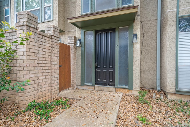 entrance to property featuring stucco siding and a gate