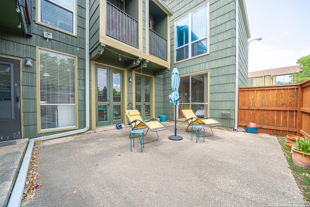 view of patio / terrace with french doors, a balcony, and fence