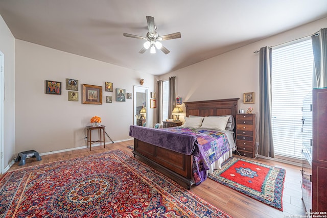 bedroom featuring ceiling fan, wood finished floors, and multiple windows