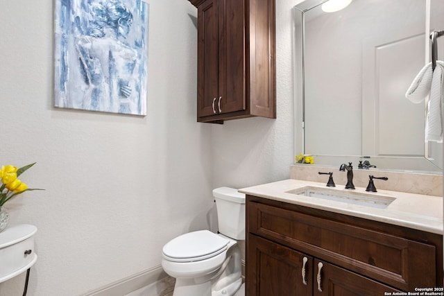 half bathroom featuring vanity and toilet