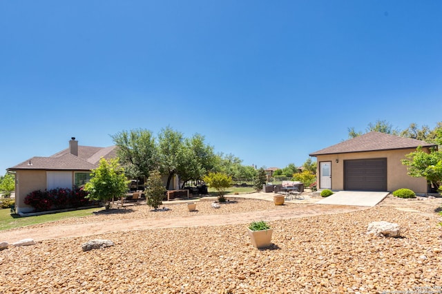 view of front of house featuring concrete driveway, roof with shingles, a patio, and stucco siding