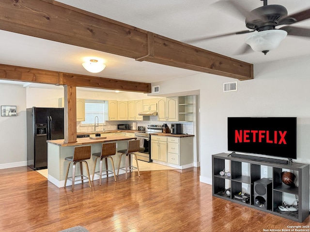 209 Lake Frst, Canyon Lake, TX 78133 - kitchen with black fridge with ice dispenser, stainless steel range with electric stovetop, a breakfast bar, visible vents, and a kitchen island