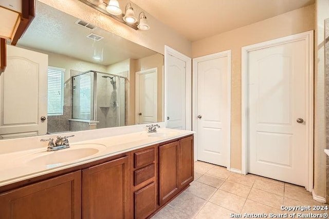 bathroom featuring double vanity, tile patterned floors, a stall shower, and a sink