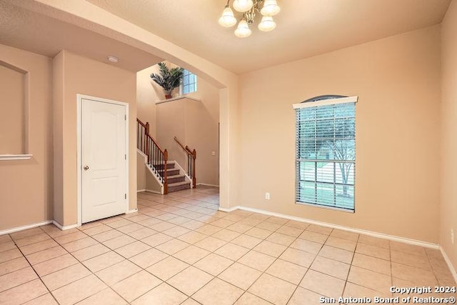unfurnished room with baseboards, a chandelier, stairs, and light tile patterned floors