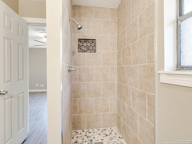 full bath featuring a tile shower, wood finished floors, visible vents, and a healthy amount of sunlight