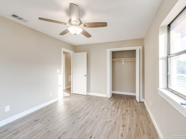 unfurnished bedroom featuring light wood-style floors, baseboards, visible vents, and a closet