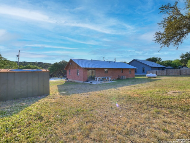 rear view of house featuring central air condition unit, metal roof, a lawn, an outdoor structure, and a shed