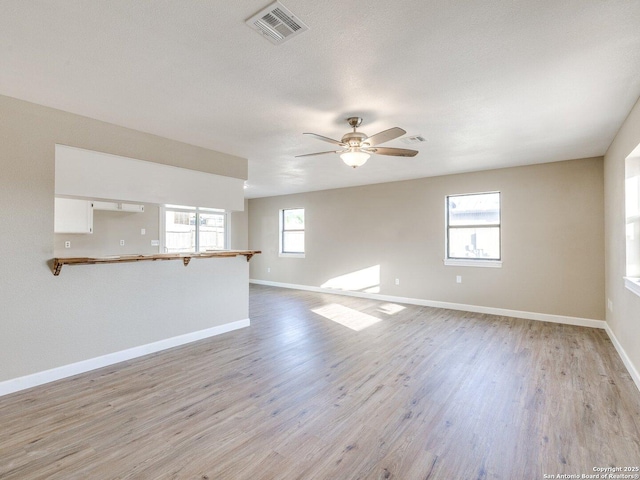 spare room featuring light wood-type flooring, baseboards, a ceiling fan, and visible vents