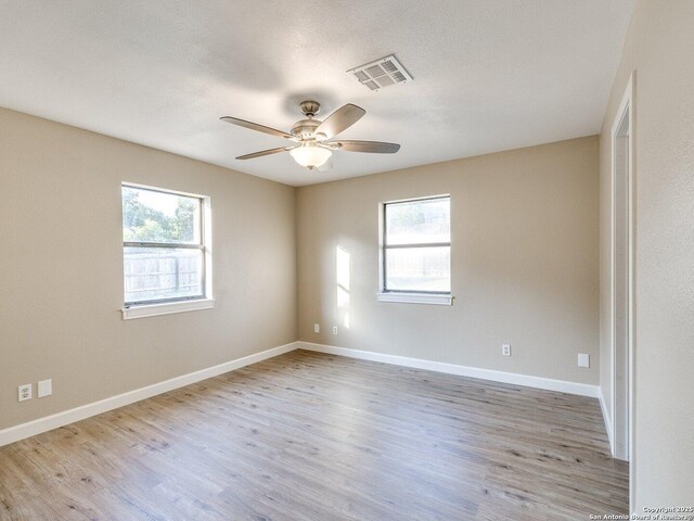 empty room with baseboards, wood finished floors, visible vents, and ceiling fan
