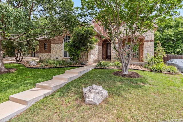 view of front of home with stone siding, a front yard, and fence