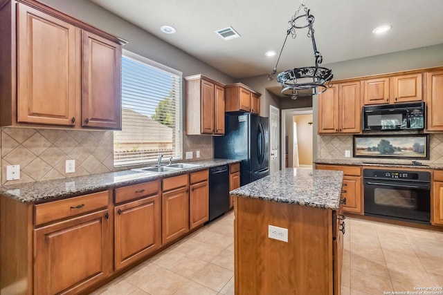 kitchen featuring a center island, a sink, visible vents, backsplash, and black appliances