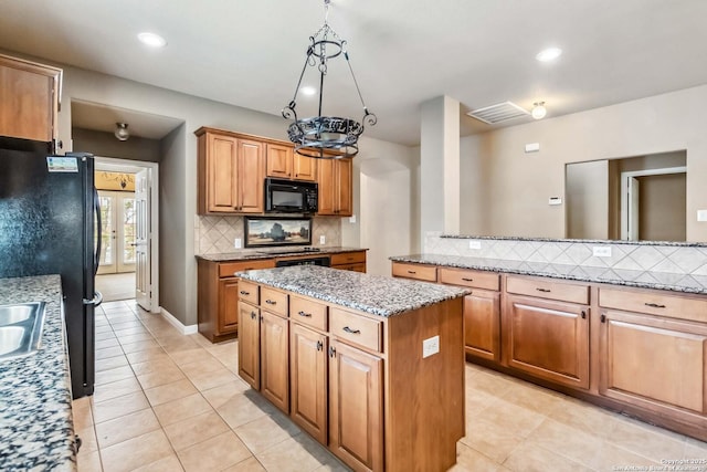 kitchen with a sink, light stone countertops, a kitchen island, decorative backsplash, and black appliances