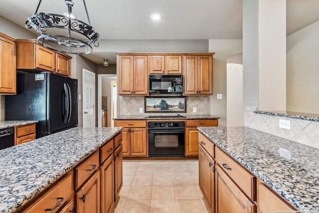 kitchen featuring tasteful backsplash, light stone countertops, and black appliances