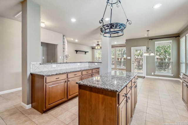 kitchen with brown cabinets, a healthy amount of sunlight, a ceiling fan, and light tile patterned floors