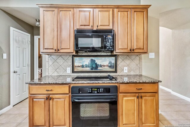 kitchen featuring light tile patterned flooring, baseboards, backsplash, light stone countertops, and black appliances