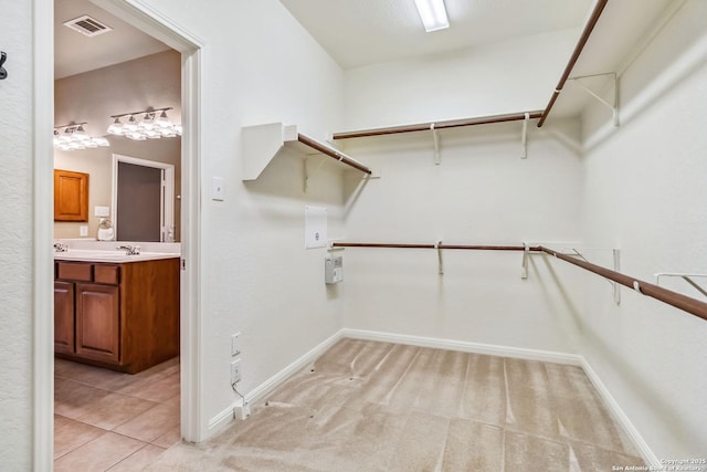 spacious closet featuring visible vents, a sink, and light tile patterned floors
