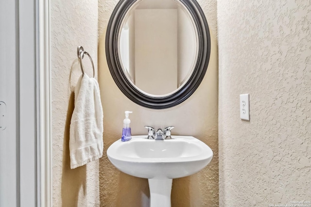 bathroom featuring a textured wall and a sink