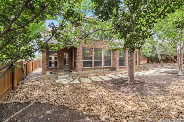 rear view of property featuring brick siding and a fenced backyard