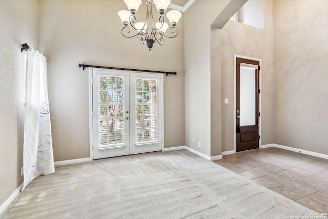 foyer entrance with french doors, a chandelier, a towering ceiling, and baseboards