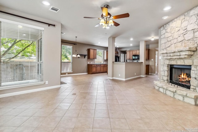 unfurnished living room featuring ceiling fan, visible vents, a fireplace, and light tile patterned floors