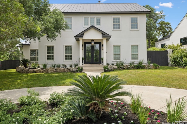 colonial inspired home featuring metal roof, french doors, a standing seam roof, and fence