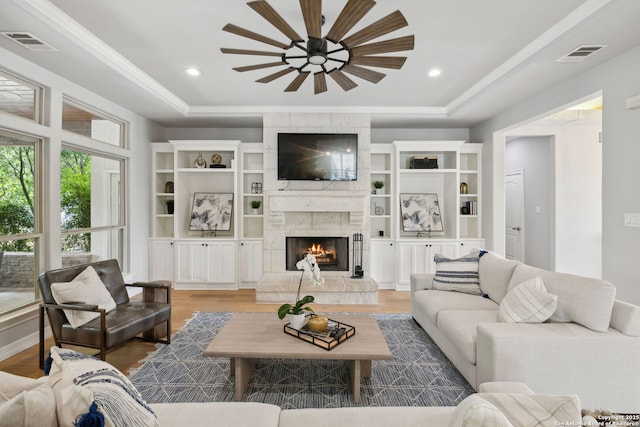 living room featuring a raised ceiling, visible vents, and ceiling fan
