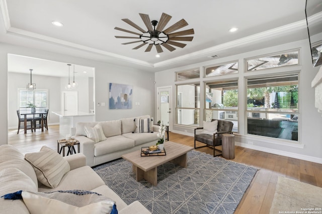 living room with hardwood / wood-style flooring, a tray ceiling, recessed lighting, and a ceiling fan
