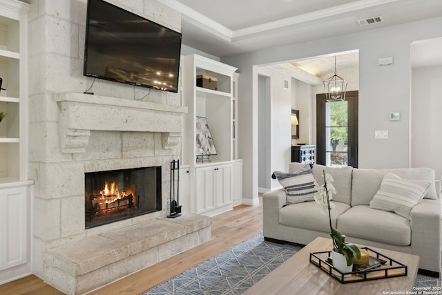 living area featuring a warm lit fireplace, ornamental molding, wood finished floors, and visible vents