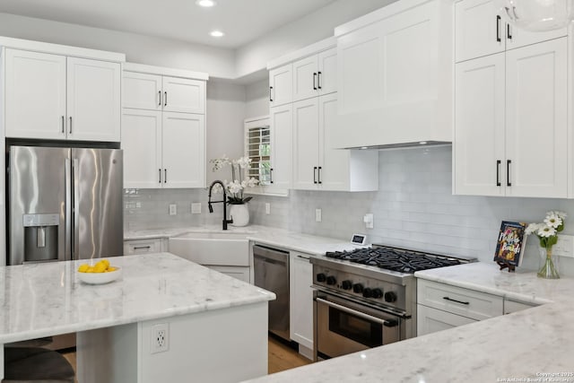 kitchen with recessed lighting, light stone countertops, stainless steel appliances, and a sink